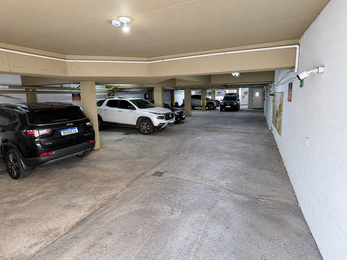 Estacionamento coberto da Dog's Company com veículos estacionados